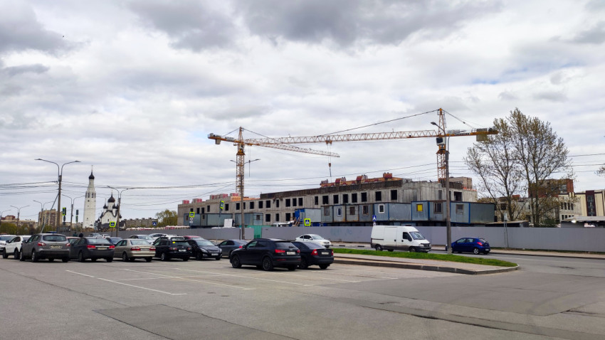 Строительство многоэтажного здания с башенными кранами и припаркованными автомобилями