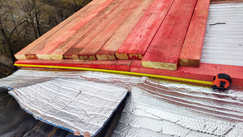 Измерение длины настила деревянных досок на кровле