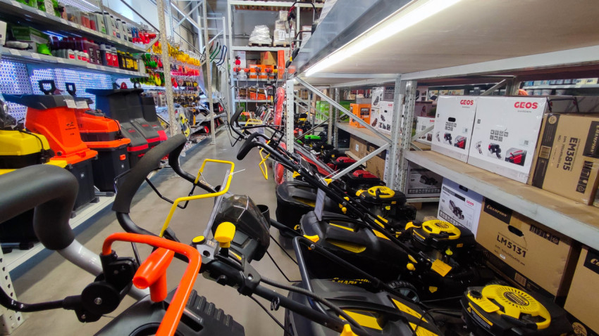 Ряд газонокосилок и садовой техники в торговом проходе