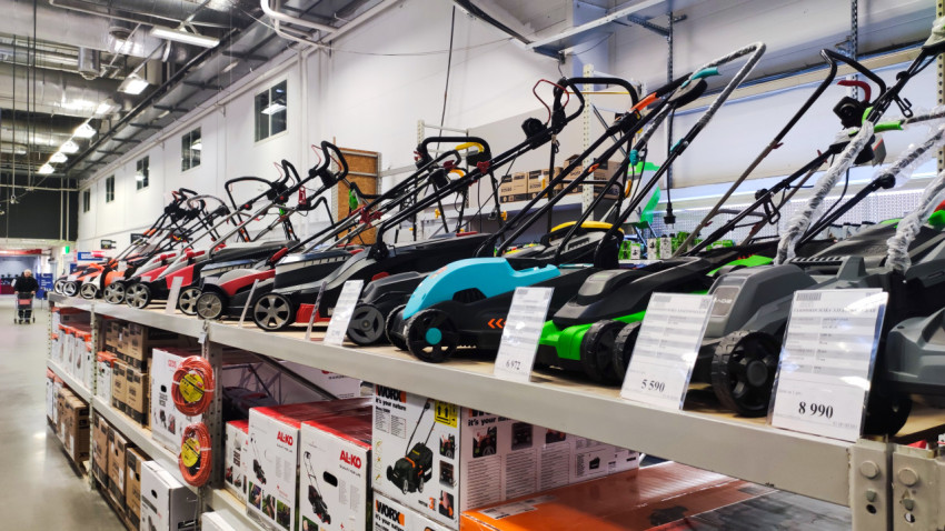 Выставочный ряд электрических газонокосилок на стеллаже магазина