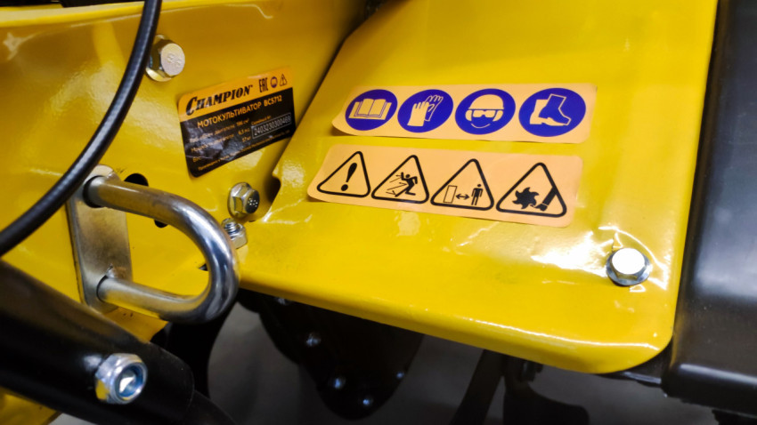 Фрагмент корпуса мотокультиватора с U-образным креплением и предупреждающими знаками