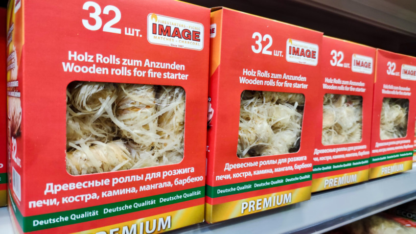 Ряд упаковок деревянных роллов для розжига на торговой полке