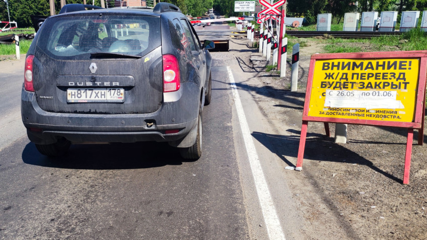 Автомобиль у железнодорожного переезда с предупреждающим знаком о закрытии