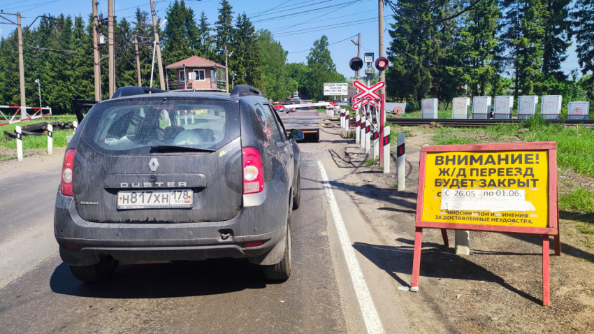 Автомобиль перед закрытым железнодорожным переездом и предупреждающим щитом