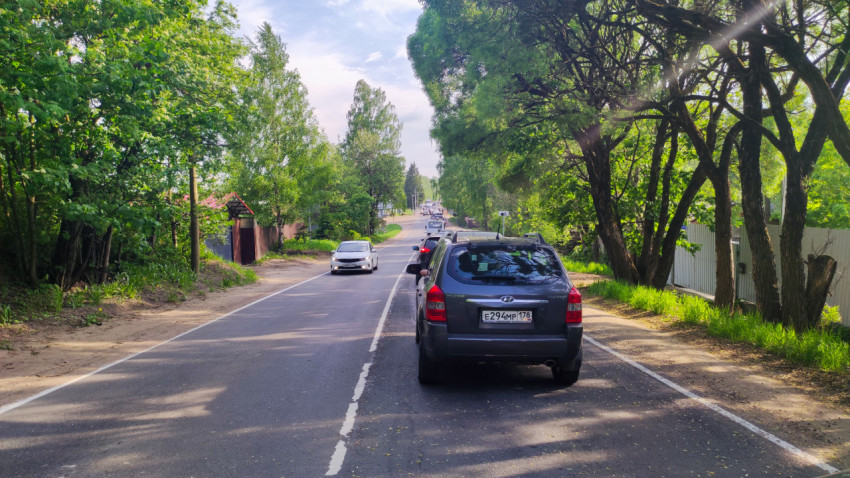 Автомобили в очереди на загородной дороге среди зелёных насаждений