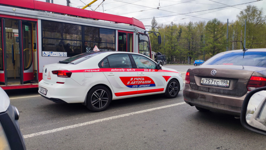 Учебный автомобиль у трамвая на городской дороге