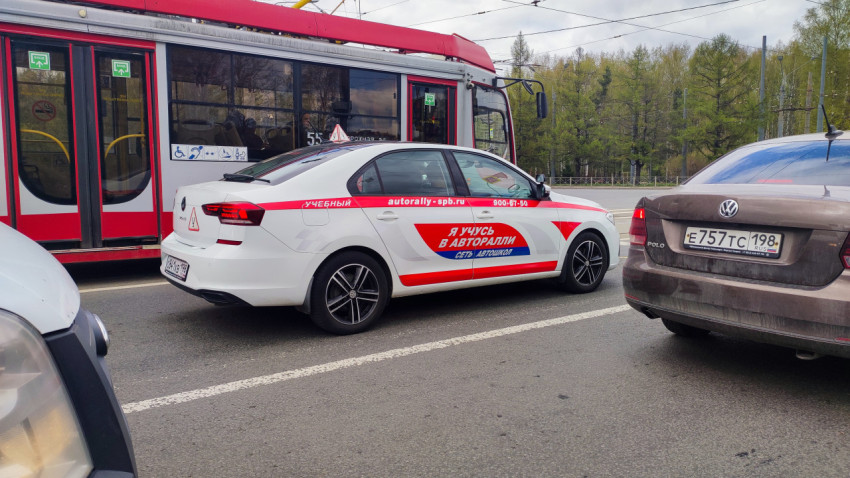 Учебный автомобиль и трамвай на фоне городской транспортной сети