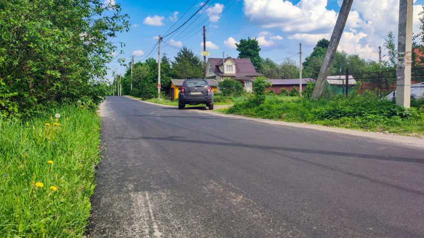 Загородная дорога с припаркованным автомобилем у жилого дома