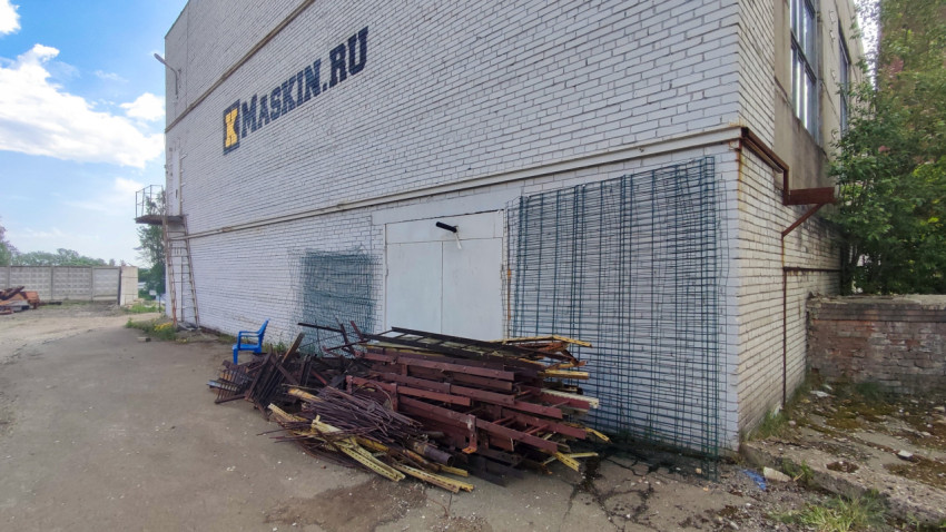 Стена промышленного здания с металлоломом и лестницей