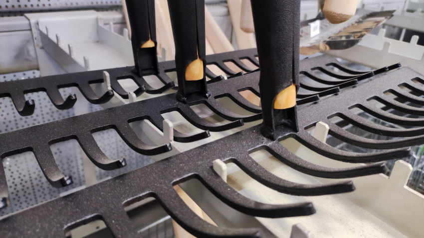 Металлические грабли с деревянными черенками на стеллаже магазина