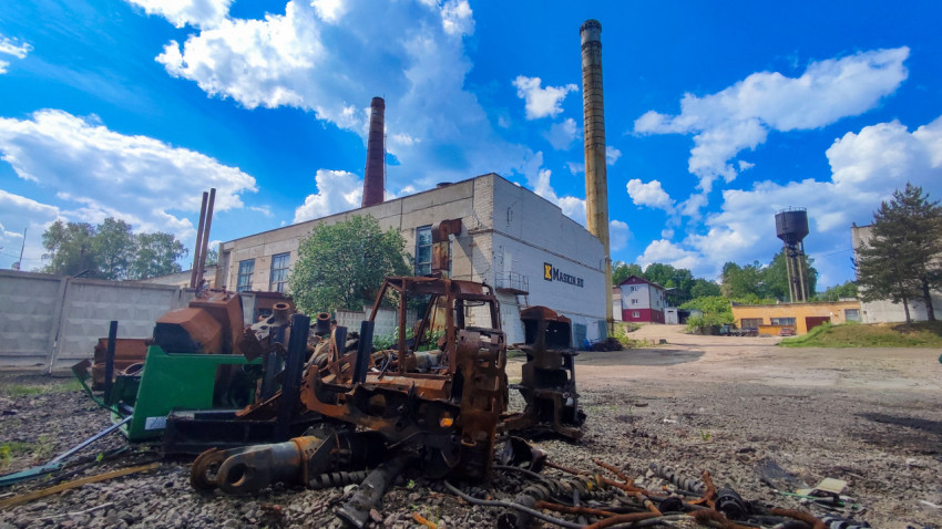 Груда металлических конструкций возле промздания с трубой и водонапорной башней