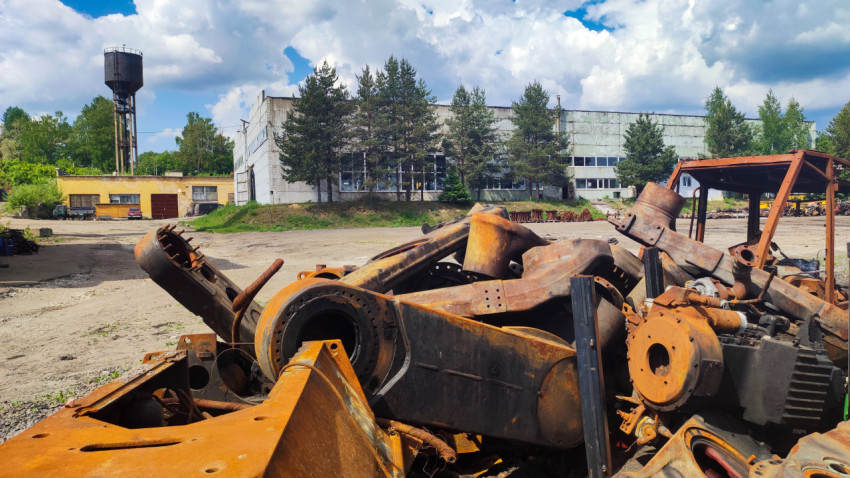 Разобранные элементы техники перед производственным зданием и водонапорной башней