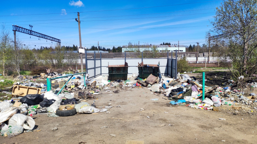 Мусорные контейнеры и окружающие отходы на открытой площадке