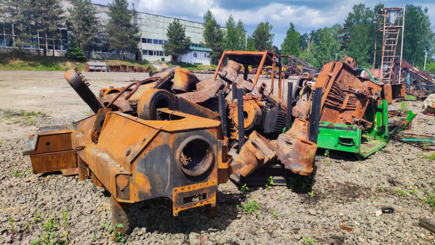 Куча ржавых элементов тяжёлого оборудования на фоне производственного здания