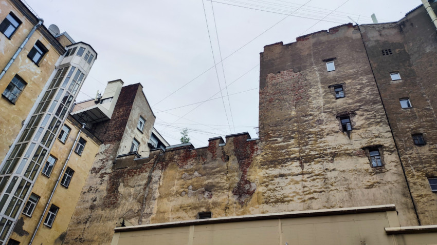 Вид снизу на стены старого двора с проводами и внешней стеклянной шахтой лифта