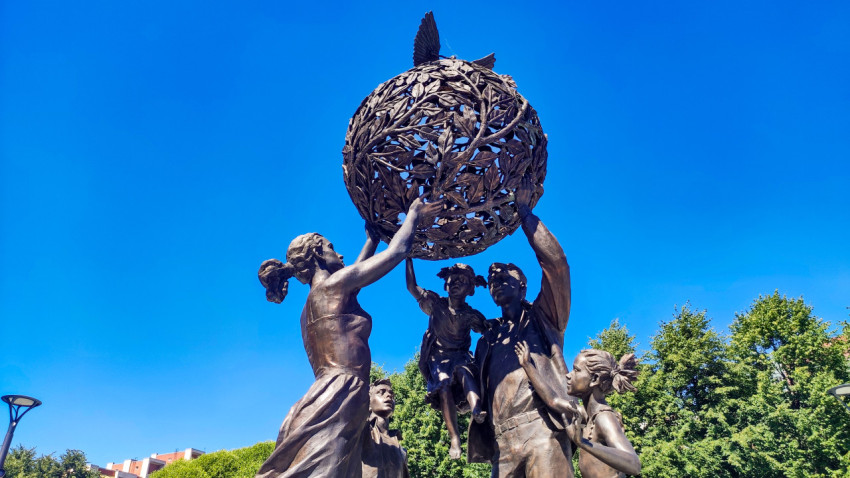 Деталь «Семья — залог мира»: ажурный земной шар из ветвей и голуби на фоне синего неба