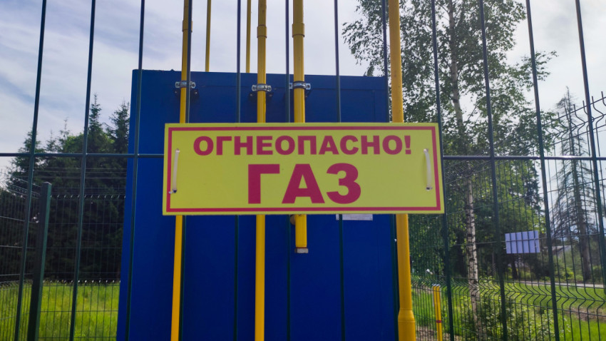 Предупреждающий знак «Огнеопасно! Газ» на фоне газового шкафа и труб