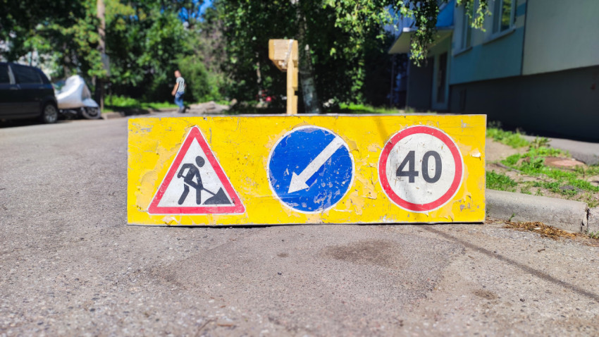 Дорожный барьер с знаками дорожных работ, объезда и ограничения скорости 40 на дворовой проезжей части
