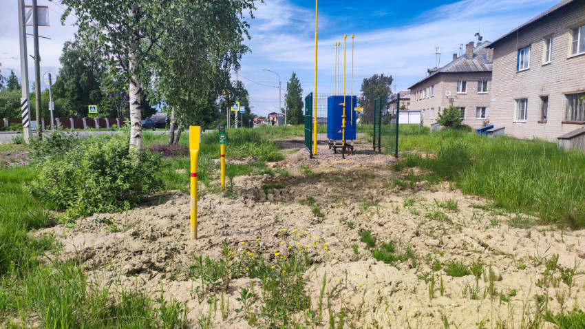 Огороженный газовый шкаф у дороги и жилого дома с сигнальными столбиками