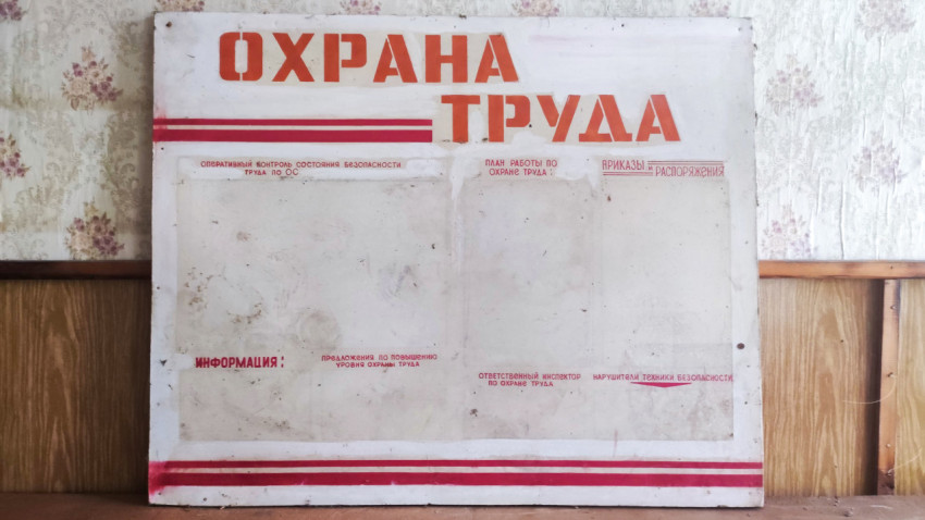 Стенд «Охрана труда» с пустыми карманами на фоне обоев и панелей