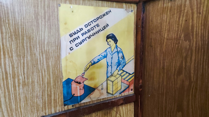 Предупреждающий плакат о работе с сургучницей в углу деревянной обшивки