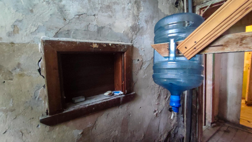 Крупный план раздаточного окна и подвешенной бутыли для воды в старом коридоре