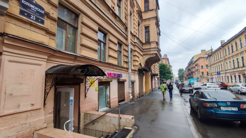 Фасад дома на Коломенской улице с вывеской Wildberries и мокрым тротуаром