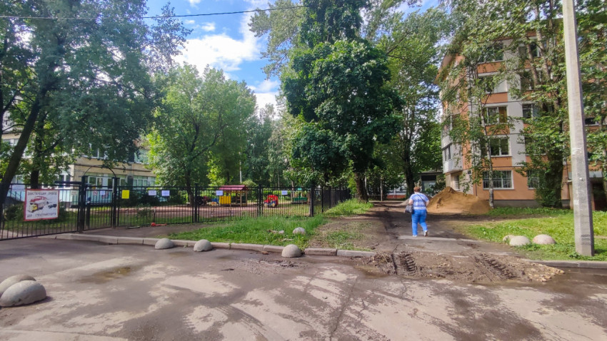 Двор с детской площадкой, лужами и кучей песка у жилого дома