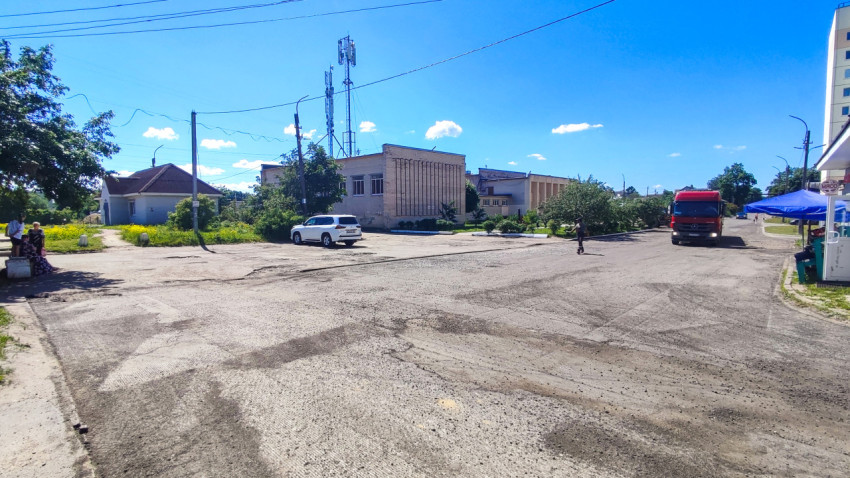 Широкая городская площадь с припаркованными машинами и грузовиком