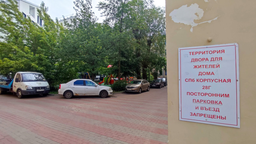 Табличка о дворовой территории для жителей на фоне припаркованных автомобилей и деревьев в жилом квартале