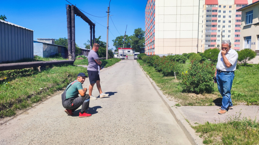 Мужчины на дороге рядом с надземной теплотрассой и многоэтажными домами
