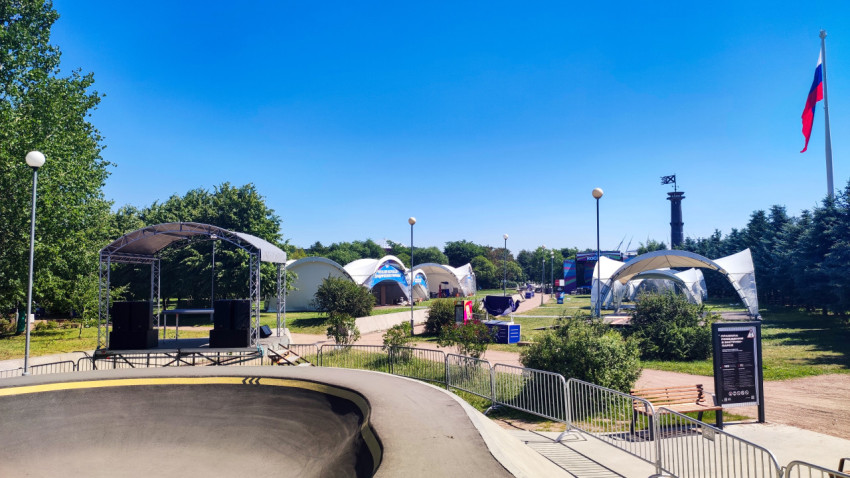 Памп-трек с бетонным контруклоном рядом с временной сценой и тентовыми павильонами в парке