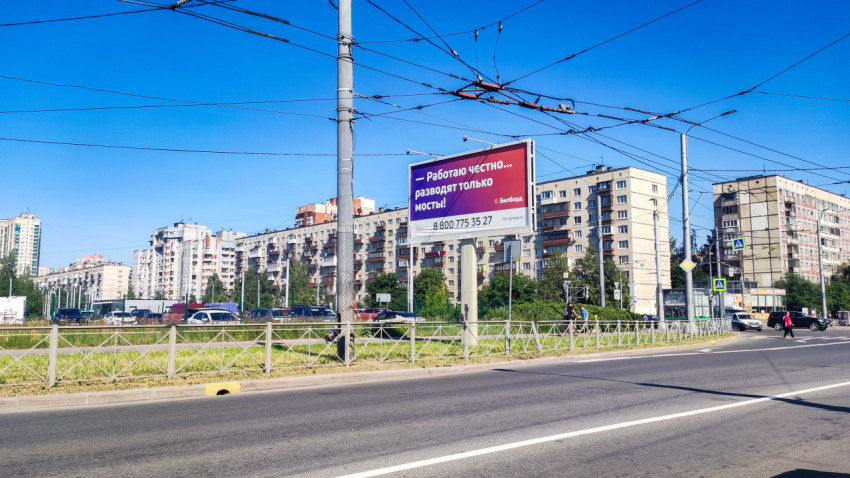 Городская магистраль с троллейбусными проводами, рекламным щитом и панельными домами на фоне