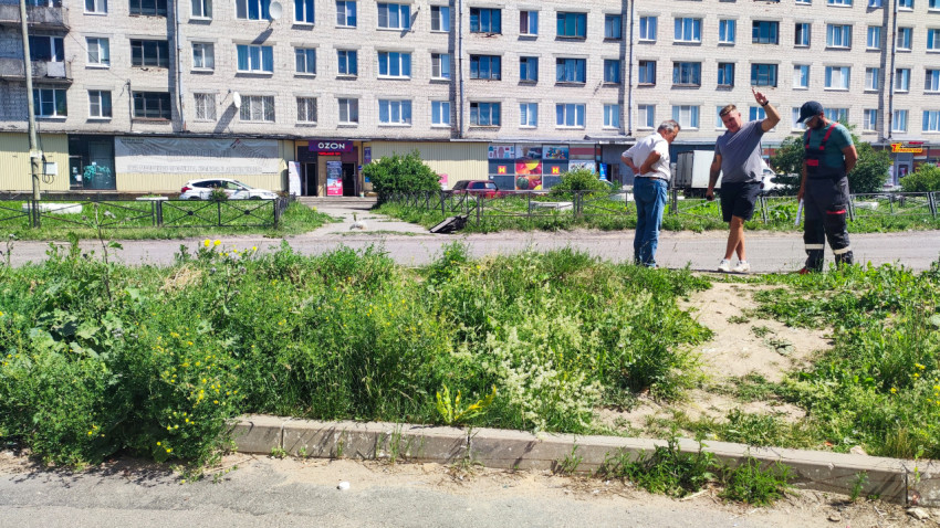 Трое мужчин обсуждают работы по благоустройству у жилого дома с магазинами на первом этаже