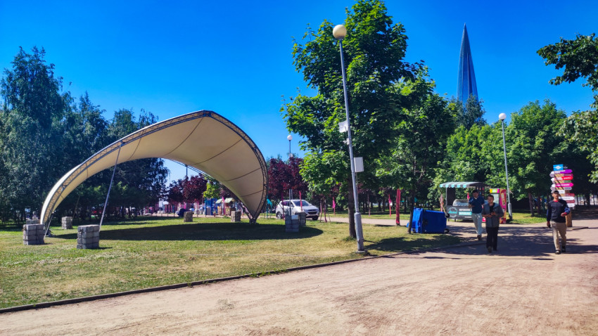 Пешеходная аллея с тентовым навесом и киоском на фоне шпиля небоскреба