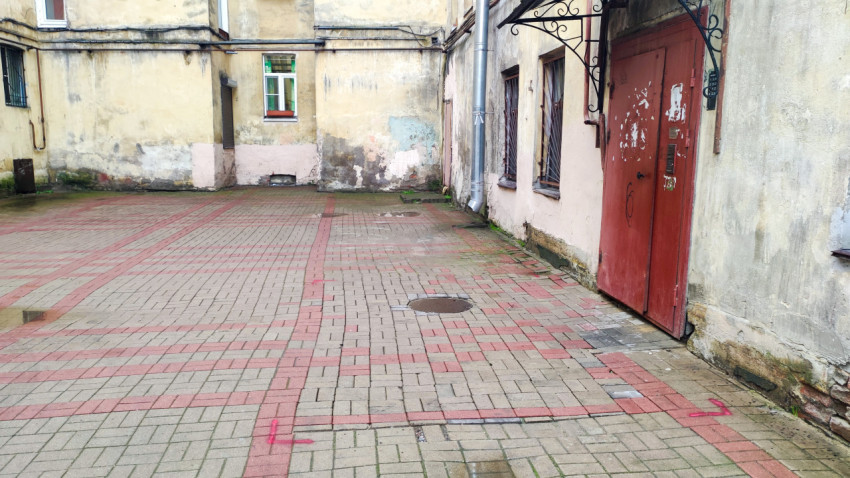 Двор-колодец с красной дверью под кованым козырьком и плиточным мощением