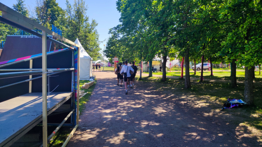 Аллея в парке с посетителями VK Fest рядом со сценическими конструкциями и шатрами