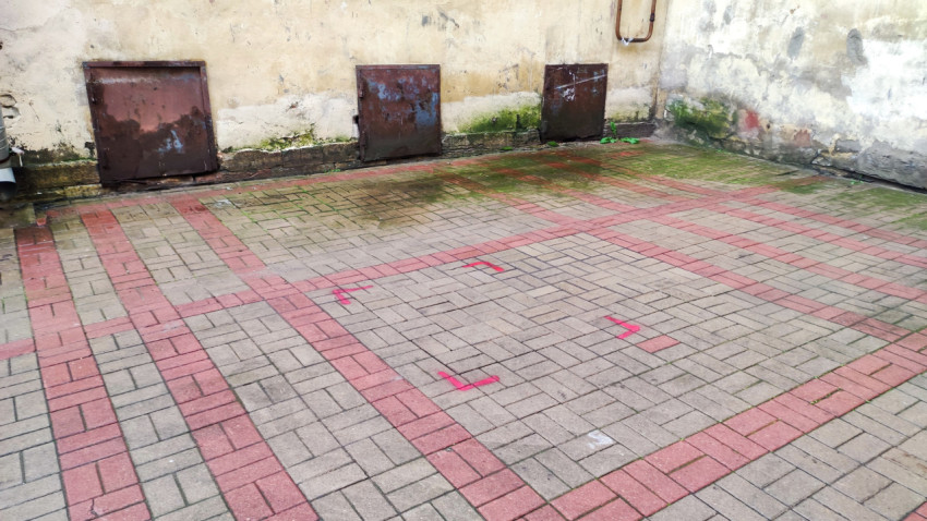 Три металлических подвальных люка на стене с зеленым налетом и плиточным мощением