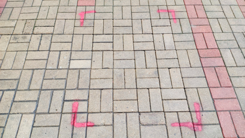Крупный план тротуарной плитки с розовой строительной разметкой и красной полосой