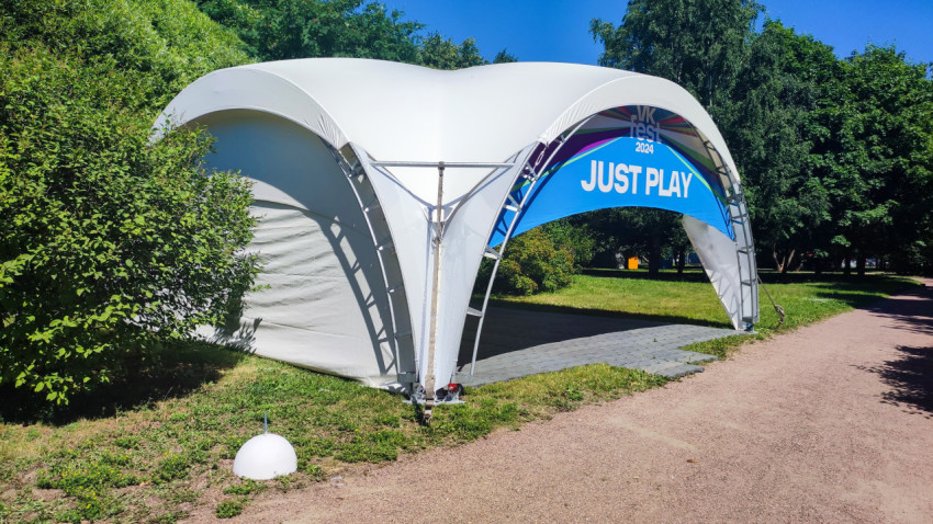 Белый шатер с брендингом VK Fest 2024 и надписью JUST PLAY у парковой дорожки