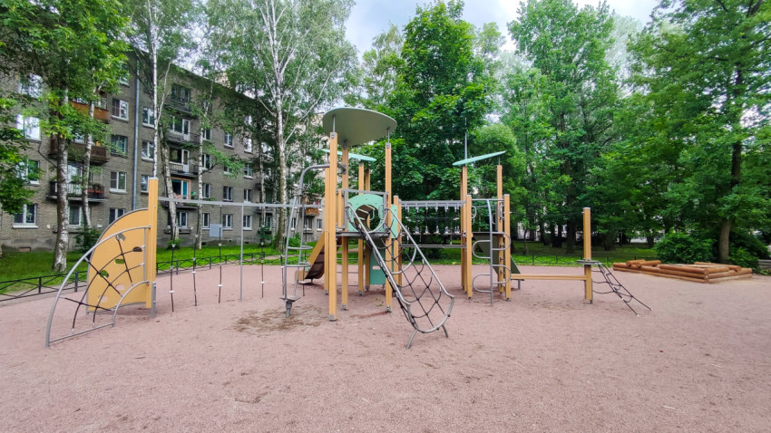 Детская площадка с высоким игровым комплексом и песочницей во дворе