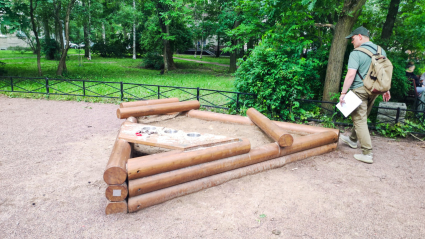 Разобранная песочница из брёвен на детской площадке во дворе жилого района