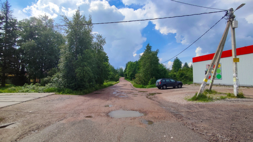 Просёлочная дорога с лужами у придорожного павильона и проводов