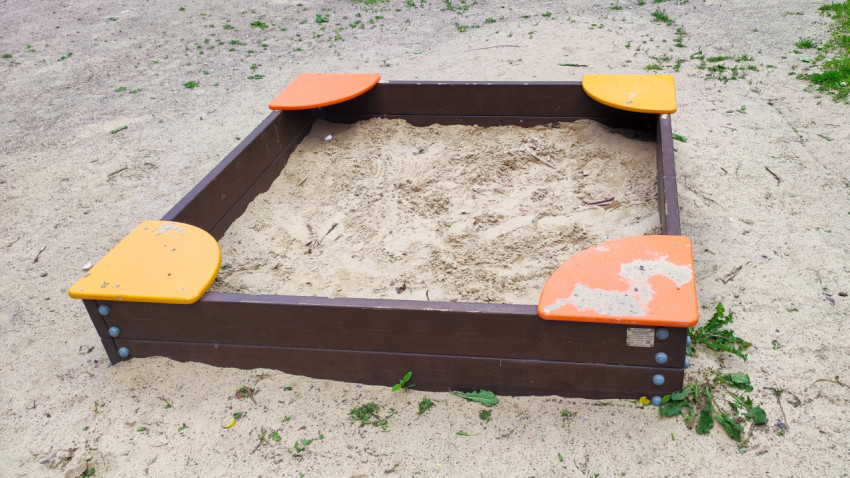 Деревянная песочница с угловыми сиденьями на песчаной площадке
