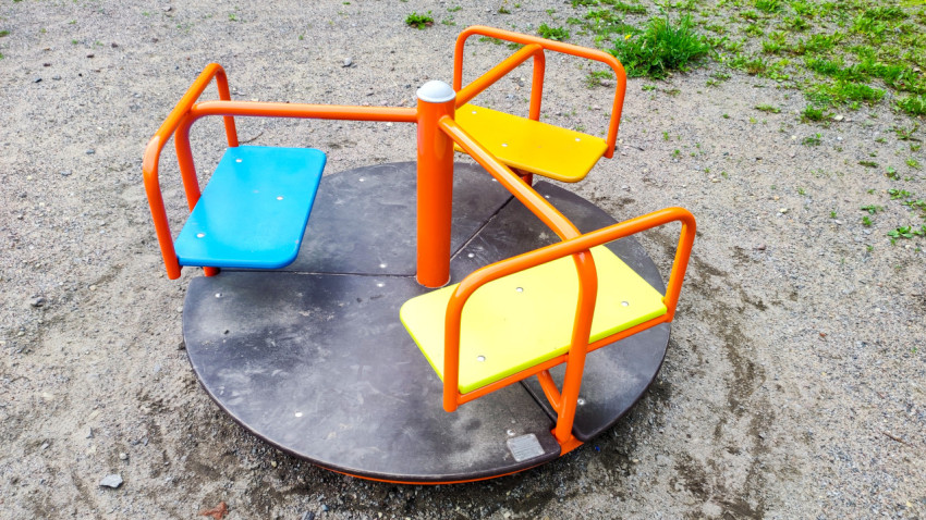 Детская карусель с тремя сиденьями на дворовой площадке