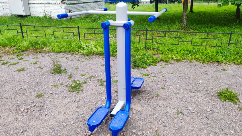 Уличный тренажёр-степпер на гравийной площадке рядом с газоном