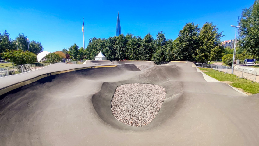 Асфальтовый памп-трек с волнами и гравийной чашей на ограждённой площадке в парке
