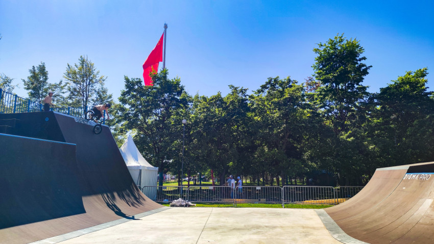 BMX-райдер заезжает на высокий квотерпайп скейтпарка рядом с флагом СССР