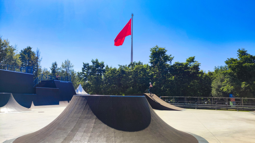 Широкий вид скейтпарка с BMX-райдером и флагом СССР на флагштоке
