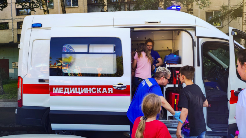 Медики работают у открытой двери автомобиля скорой помощи во дворе многоквартирного дома